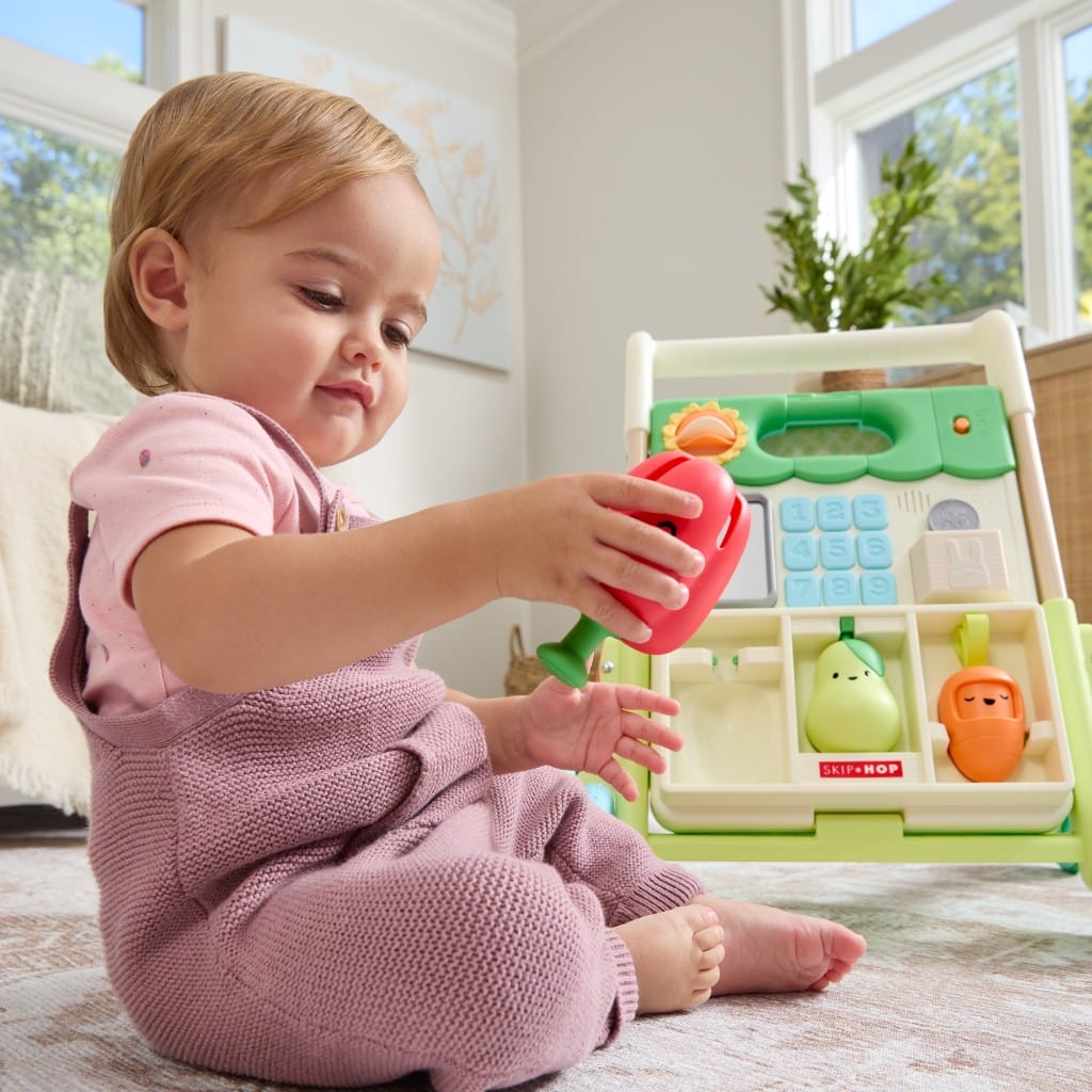 Baby holding the detachable red pepper beside the Farmstand walker