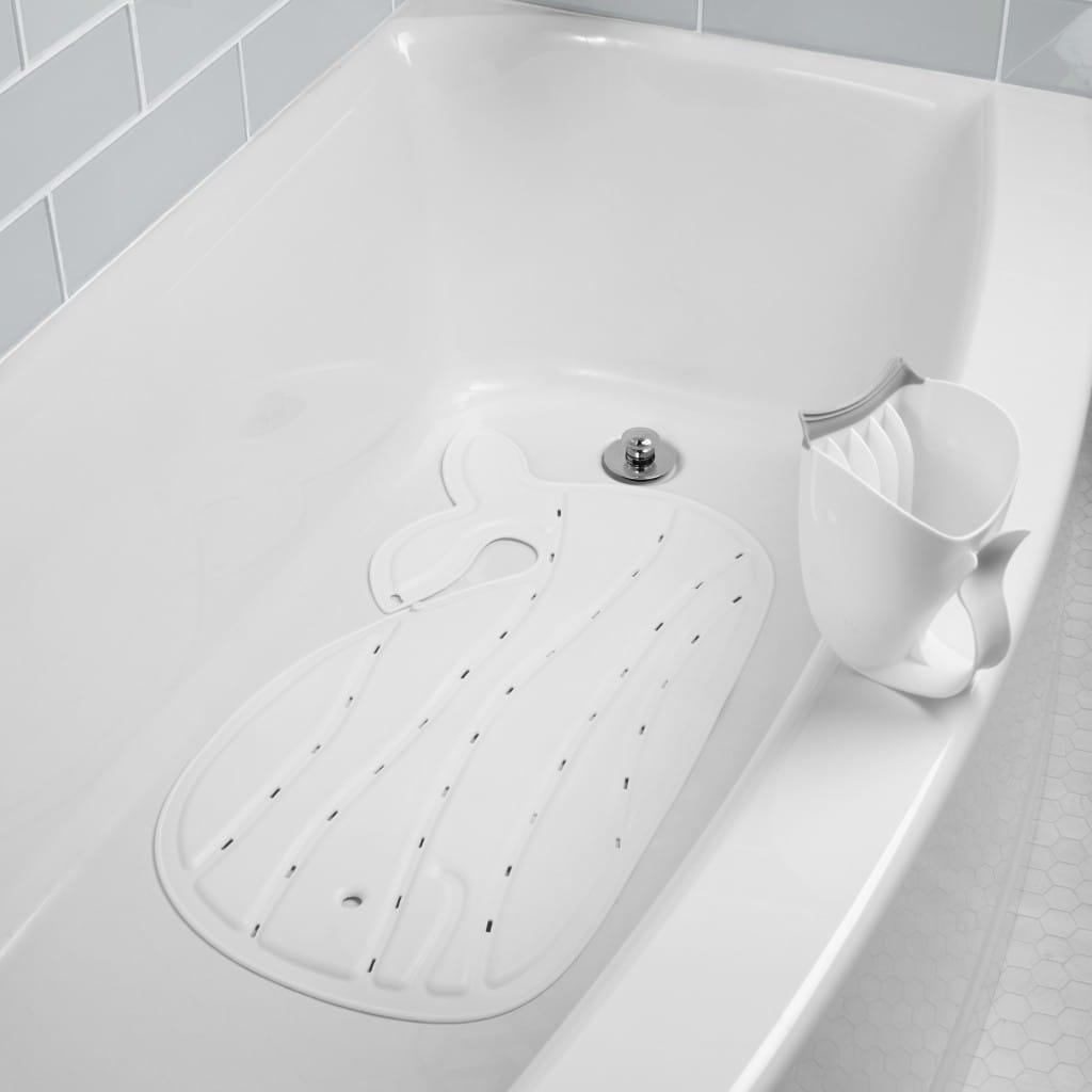 White Moby bath mat lying flat in a bath beside matching bath accessories