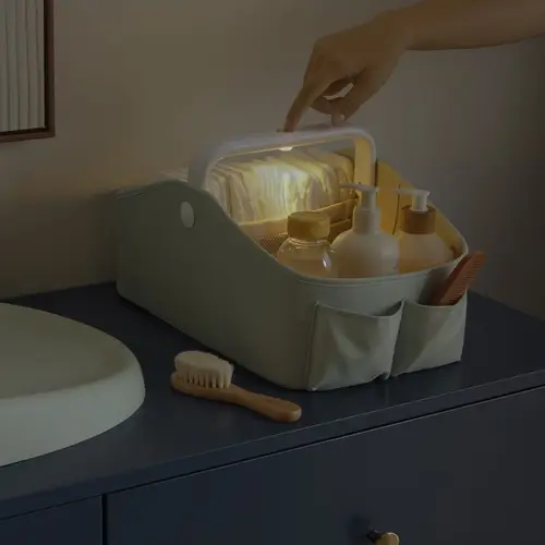 Skip Hop Sage Light Up Nappy Caddy Touch Sensitive Handle Light Hand touching the Sage caddy handle to activate its light